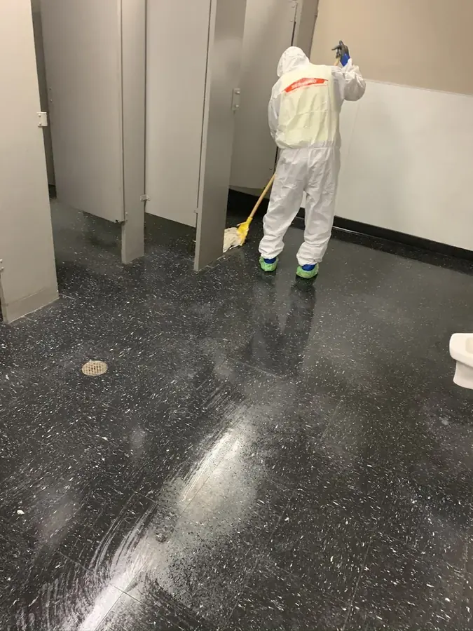 Technician in protective gear cleaning a contaminated black water floor in a Bronx, NY building